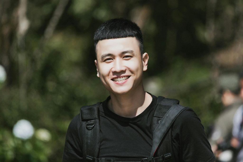 Portrait of a cheerful young man smiling outdoors with a blurred natural background.